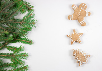 Gingerbread in the shape of a man, a Christmas tree and a star on a white background, copyspace. The branches of the Christmas tree.