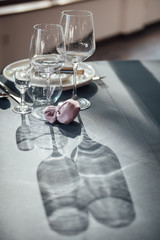 Glasses, flowers, fork, knife served for dinner in restaurant with cozy interior,