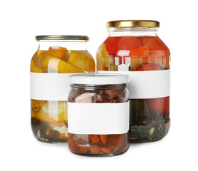 Jars of pickled vegetables with blank labels on white background