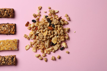 Healthy granola bars and ingredients on pink background, flat lay