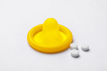 Yellow condom and birth control pills on white background. Safe sex concept