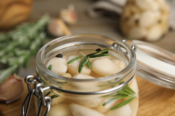 Jar of pickled garlic on wooden table, closeup