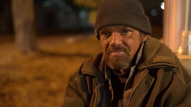 Face of lonely cold homeless man on the street at night.