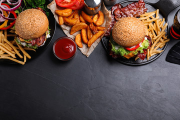Flat lay composition with fresh bacon burgers and fries on grey table. Space for text