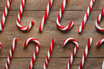 Flat lay composition with candy canes on wooden background. Traditional Christmas treat