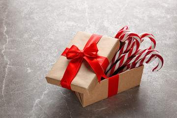 Candy canes in gift box on light grey marble table. Traditional Christmas treat