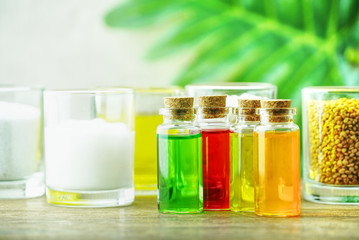 Four organic oil in the bottles on the table for produce apothecary cosmetic product with green leaf decorate on wall background