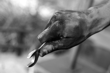 Dirty worker holding wrench on blurred background, closeup of hand. Black and white effect