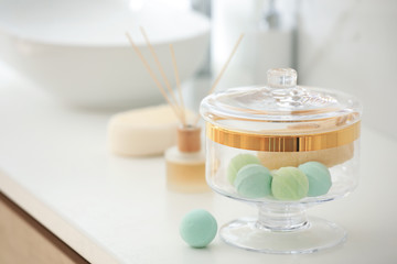 Jar with bath bombs and loofah sponge on white countertop in bathroom
