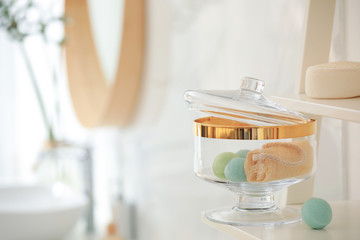 Jar with bath bombs and loofah sponge on shelving unit in bathroom