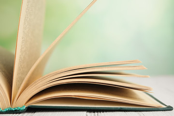 Fototapeta premium Open book on white wooden table against blurred green background, closeup