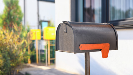 Black mailbox near house outdoors on sunny day