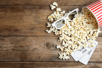 Obraz na płótnie Canvas Popcorn, cinema tickets and 3d glasses on wooden background, flat lay. Space for text