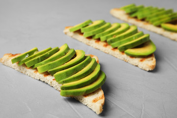 Tasty toasts with avocado on light grey table, closeup