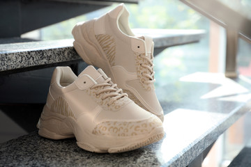 Pair of stylish women's sneakers on grey marble stairs indoors