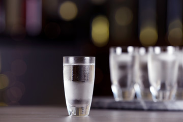 Shot of vodka on table against blurred background - obrazy, fototapety, plakaty