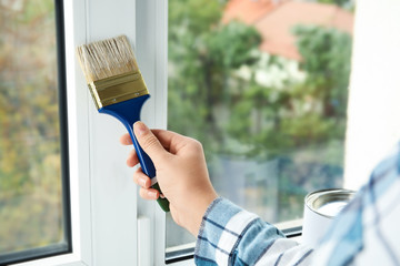 Woman painting window frame at home, closeup