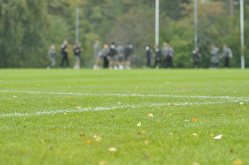 On a football practise and on a green field on a rainy, cold and grey Autumn afternoon with soccer players on a background