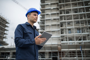 Site manager using tablet in front of a construction site