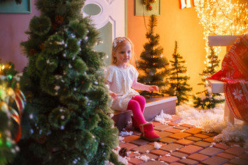 Fototapeta na wymiar little girl sitting on the doorstep in New Year's decorations