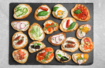 Different bruschettas on light grey marble table, top view