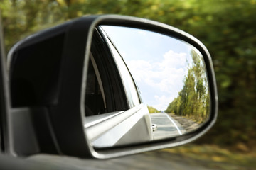 Fototapeta na wymiar Closeup of car side rear view mirror on sunny day