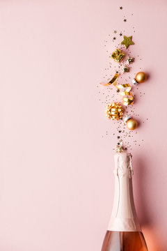 Flat lay of Celebration. Champagne bottle and golden decoration on pink background