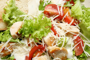 Delicious Caesar salad with fresh ingredients as background, closeup