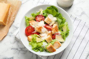 Delicious fresh Caesar salad in bowl on white marble table, flat lay