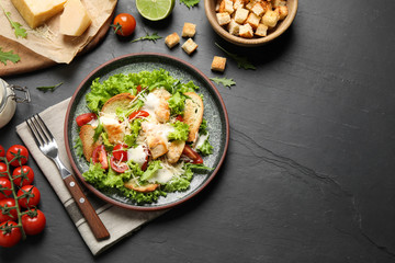Delicious fresh Caesar salad on black table, flat lay. Space for text