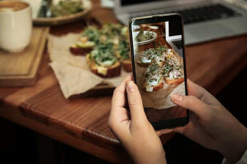 Food blogger taking photo of her lunch at cafe, closeup