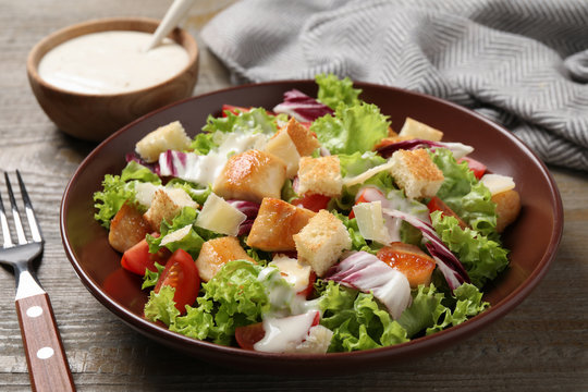 Delicious fresh Caesar salad on wooden table