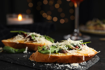 Delicious bruschettas with beef and cheese on black table, closeup