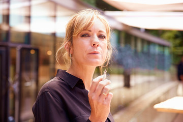 Middle aged woman smoking cigarette while standing outdoor