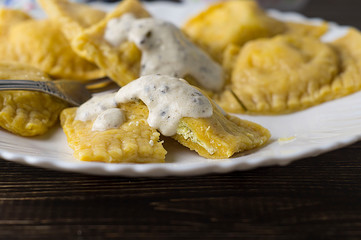 Ravioli with cottage cheese and herbs. Milk sauce with pesto. Traditional dish.