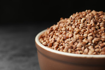 Uncooked buckwheat grains on grey table, closeup