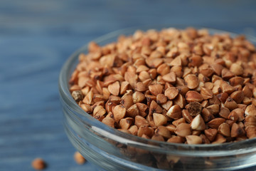 Uncooked buckwheat grains in glass bowl, closeup