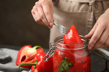 Woman with jar of pickled peppers at table, closeup