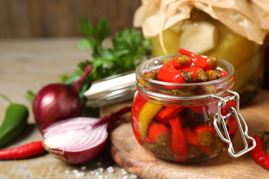 Glass Jar With Pickled Peppers On Wooden Table