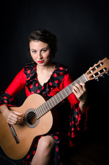 Obraz premium Carmen beautiful woman in red dress, with guitar on dark background