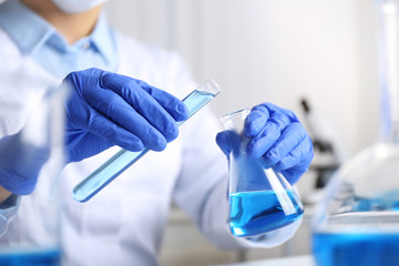 Doctor pouring blue liquid into flask, closeup. Laboratory analysis