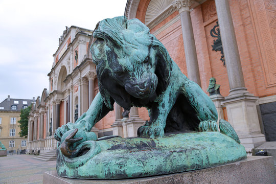 Bronze statue of a lion fighting against a snake in front of Ny Carlsberg Glyptotek in Copenhagen, Denmark
