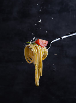 Fototapeta tagliatelle with tomato and pesto on fork. Italian food. Dark background