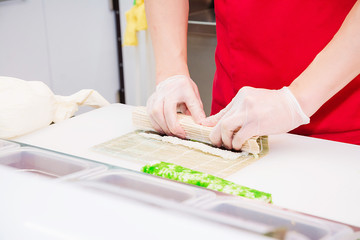 Cooking sushi rolls with his hands.