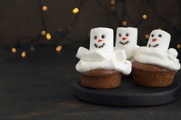 Christmas chocolate cupcakes with snowman decor. on dark background.