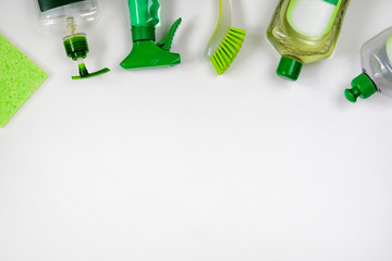 Detergents in plastic bottles. Сleaning accessories. Flat lay of green and white cleaning supplies...