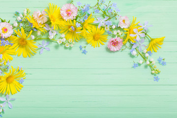 frame of beautiful flowers on green wooden background