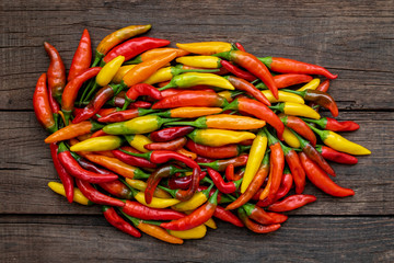 Different colorful varieties of hot peppers on wooden background