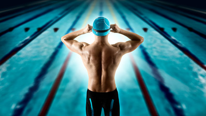 Swimmer jumping from starting block in a swimming pool