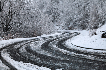 Heavy Snowfall. Snowy road through forest, steep turn of road - 300729281
